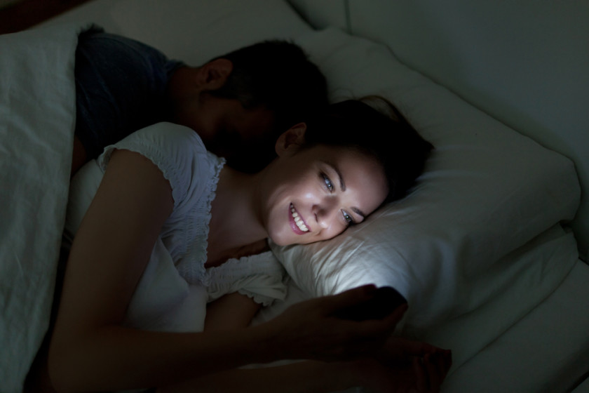 Woman using smartphone in bed at night