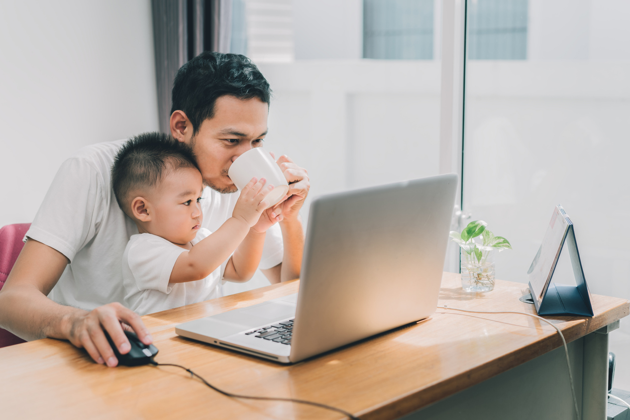 man working from home with a child on his lap